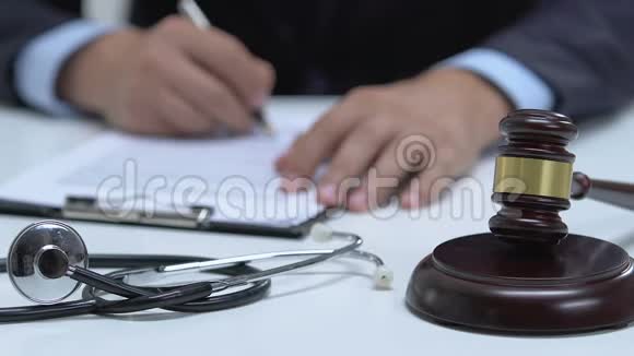 男性法官签署文件和录音槌桌上听诊器疏忽视频的预览图