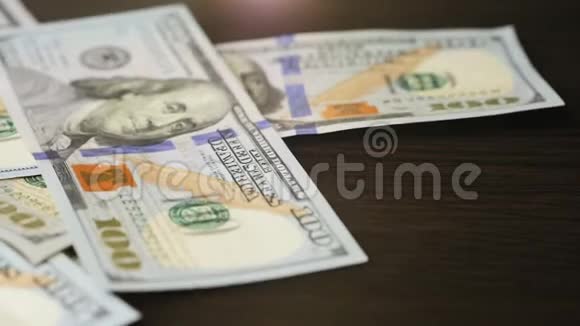 一百美元钞票落在棕色木桌上视频的预览图
