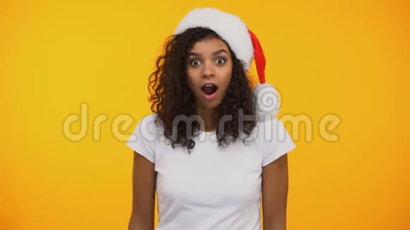 圣诞老人帽子里快乐的混血女人说哇带着礼物高兴地惊讶了视频的预览图