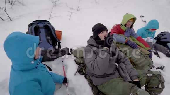 4个人在冬天在森林里徒步旅行躺在雪地里检查背包视频的预览图