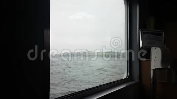在波涛汹涌的海洋和灰色的天空上眺望渡船窗外视频的预览图