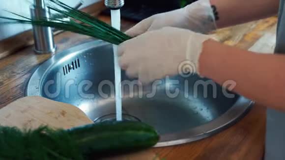 女手戴手套在厨房水槽里洗新鲜韭菜视频的预览图