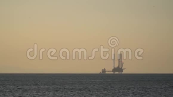 海上大型石油钻井平台剪影橙色雾背景日落视频的预览图