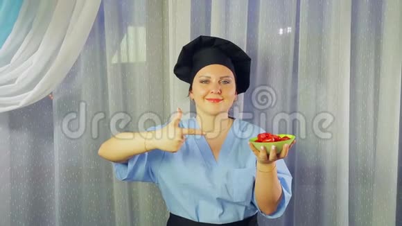 女人穿着围裙做饭微笑着手拿着盘子里的樱桃番茄用手展示视频的预览图