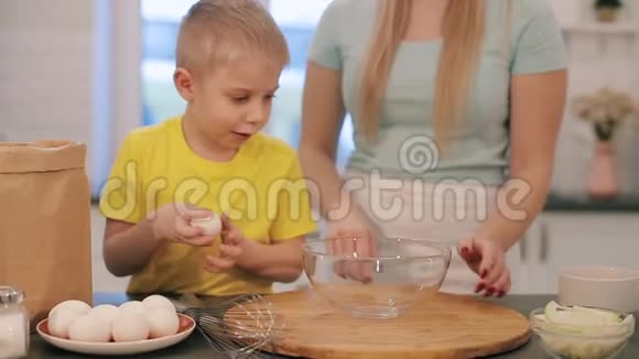 漂亮的白种人孩子蓝眼睛烤蛋糕一位年轻的母亲教她的儿子如何视频的预览图