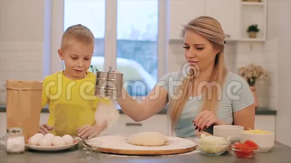 一家人在厨房里玩得很开心可爱的小男孩和他漂亮的妈妈穿着五颜六色的鲜艳衬衫的正面景色视频的预览图