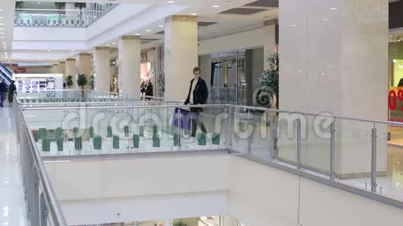 时髦的家伙提着五颜六色的纸袋走过购物中心视频的预览图
