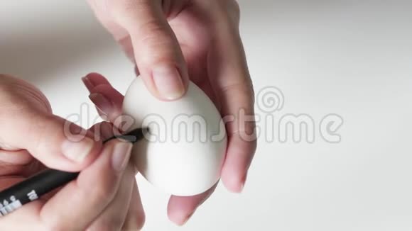 复活节时一个拿着记号笔的不可辨认的女人在鸡蛋上画黑色图案复活节假期的概念视频的预览图