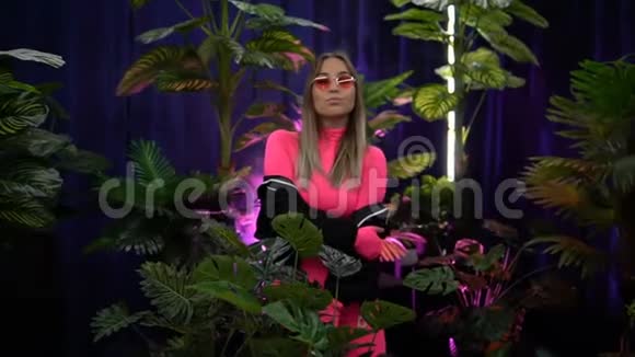 穿粉色衣服的时髦女郎站在绿色植物中间视频的预览图