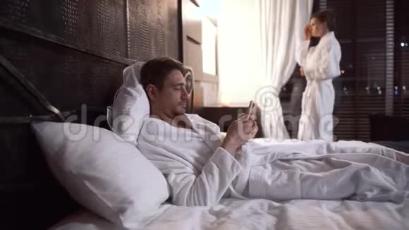 在舒适的酒店里成年人躺在床上用手机发短信视频的预览图