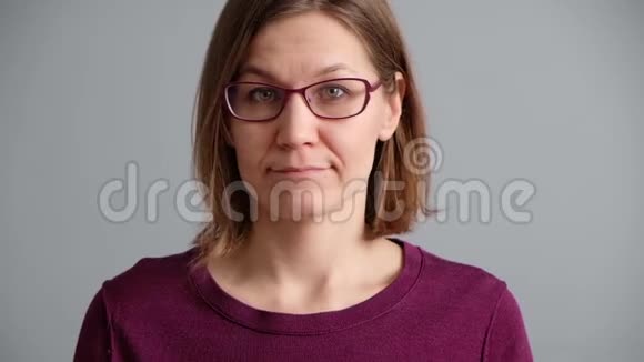 女人在灰色背景下思考并有想法美丽的白种人女人穿着毛衣和眼镜视频的预览图