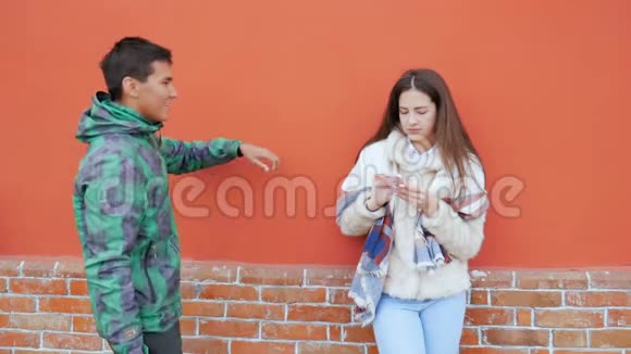 一个年轻人和一个女孩站在房子墙附近的街道上说话视频的预览图