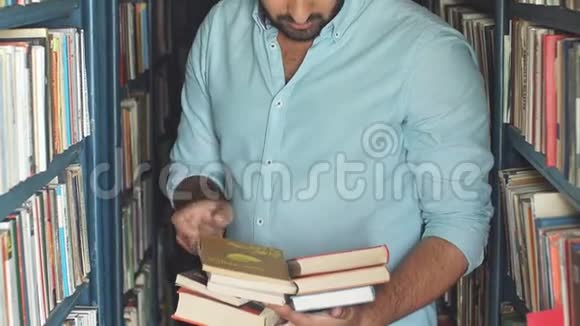 年轻的阿拉伯胡子男学生在图书馆书架间挑选书视频的预览图