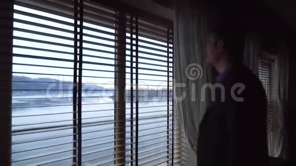 成年高个子男人来到窗口欣赏风景酒店房间里英俊的商人视频的预览图