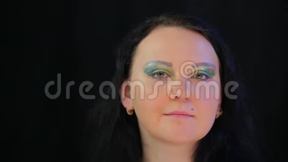 一个肤色浅黑的女人的脸上带着眼妆明亮的绿色闪闪发光视频的预览图