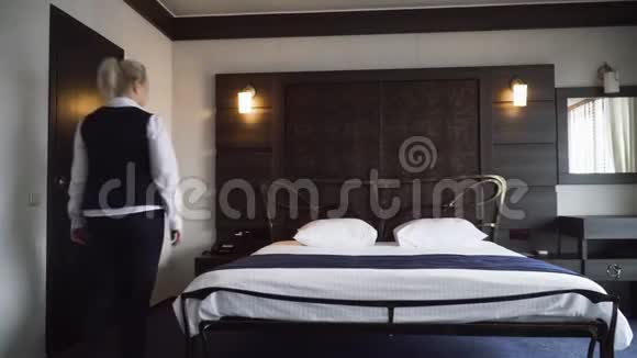 女佣铺了一张双人床在一间舒适的小旅馆房间里把枕头伸直视频的预览图