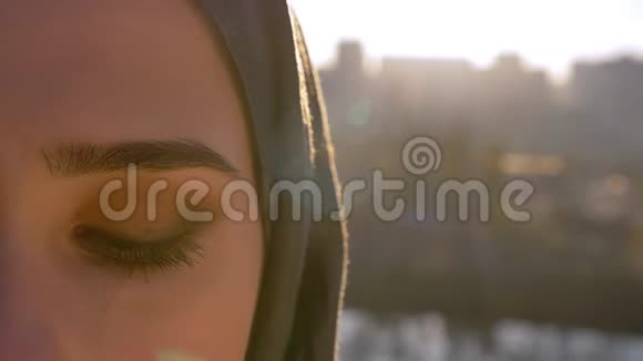 hijjab年轻女性特写半脸的肖像直视镜头背面是城市打开眼睛视频的预览图