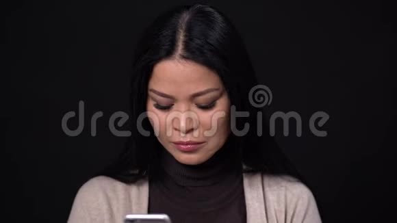 黑人背景上的布鲁内特女人眼睛眯着在电话上说话视频的预览图