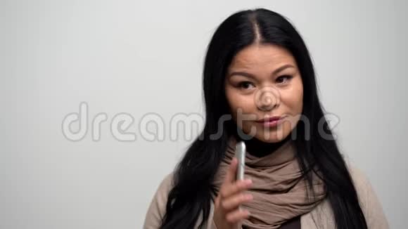 美丽的亚洲女人在白色背景上说话在电话上视频的预览图
