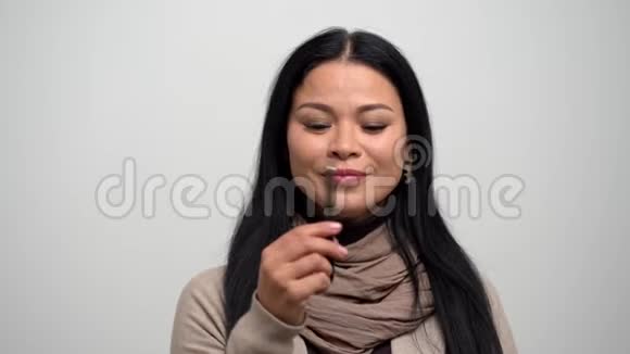 穿着白色背景的米色毛衣眼睛窄的亚洲女人视频的预览图
