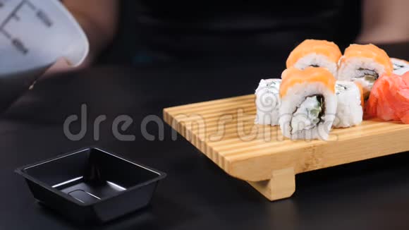 慢运动食品概念黑色背景下将酱油倒入盘子的特写时尚的寿司视频的预览图