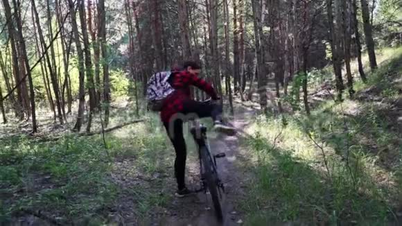 在森林小径上骑山地自行车的活泼的女人在树林里骑自行车的女人视频的预览图