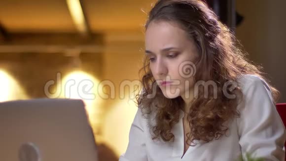 年轻卷发女子的特写肖像靠在椅子上在办公室里表现出强烈的沮丧和失望视频的预览图