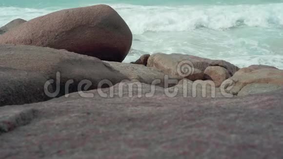 塞舌尔普拉斯林岛沙滩上干净的水和背景上沙子上的大石头人类视频的预览图