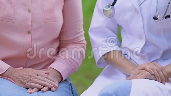 护士牵着坐在公园长凳上的老妇人的手病人支持视频的预览图