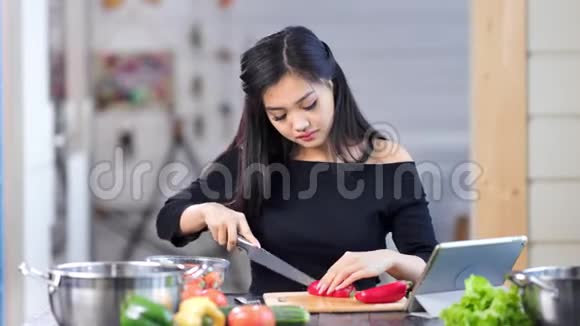 可爱的年轻亚洲女性家庭主妇在厨房做新鲜健康饭菜时的肖像视频的预览图