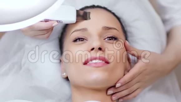 快乐的白种人年轻女士在美容院享受面部超声波去死术视频的预览图