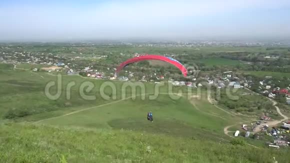 滑翔伞从青山上起飞视野的田野蓝天的云彩和不同的房子视频的预览图
