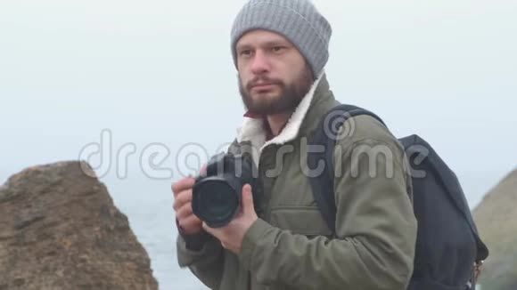 一位留着胡须的户外摄影师捕捉一片暴风雨的大海视频的预览图