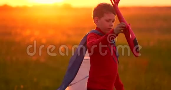 那个男孩在日落时手里拿着一架飞机跑过田野视频的预览图