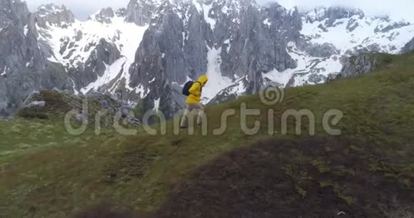 徒步旅行者在白雪皑皑的群山背景下登上一座小山视频的预览图