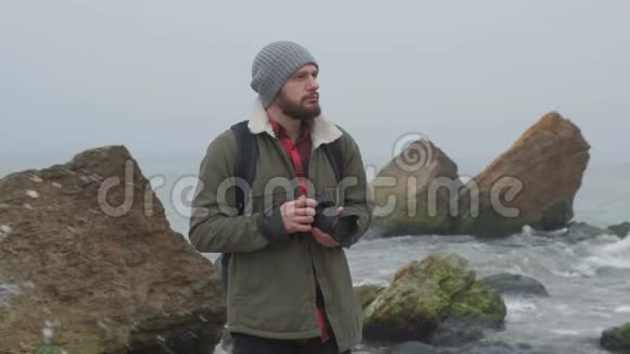 一位留着胡须的户外摄影师捕捉一片暴风雨的大海视频的预览图