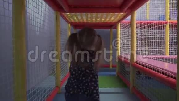 女孩在操场上的儿童迷宫中穿过隧道视频的预览图