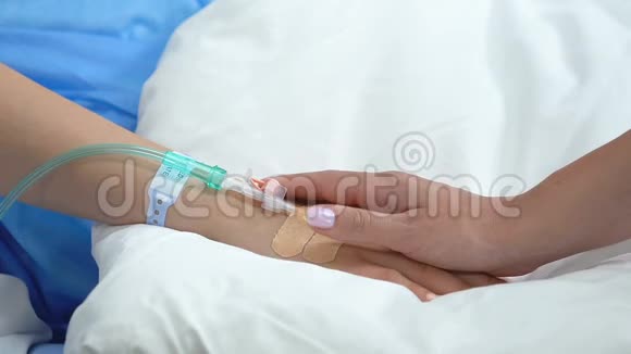 母亲抚摸女儿的手滴滴躺在病床上家庭支持视频的预览图