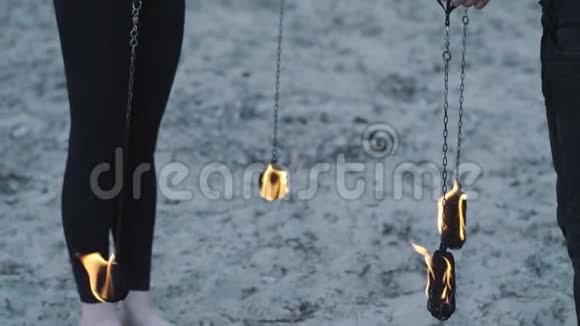 雄性和雌性的腿站在沙子上拿着燃烧的火球在户外表演火焰艺术家视频的预览图