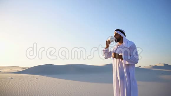 早上好在巨大的沙漠中间的男性酋长在蓝天和露天沙丘上喝杯咖啡视频的预览图