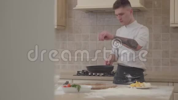 穿厨师制服的年轻人把盐放进煎锅里把肉扔进煎锅里专业厨师烹饪食物视频的预览图