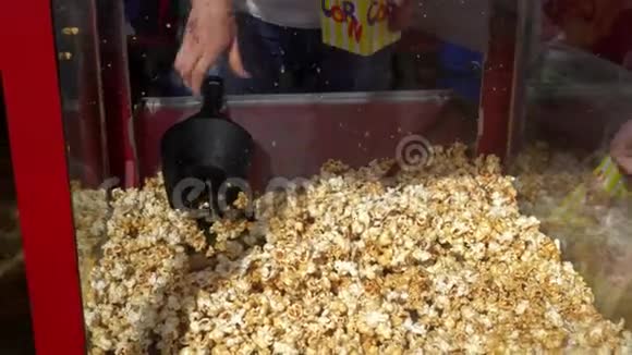 女人的手把甜爆米花放进纸袋里在户外集市上卖爆米花视频的预览图