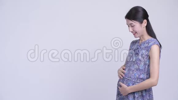 快乐的亚洲孕妇向后展示一些东西视频的预览图