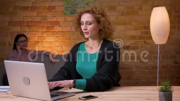 在笔记本电脑上工作的年轻女商人的特写镜头打电话在室内放松悠闲视频的预览图