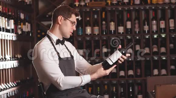 优雅的葡萄酒销售商在一家葡萄酒商店里拿着一瓶葡萄酒和阅读标签视频的预览图