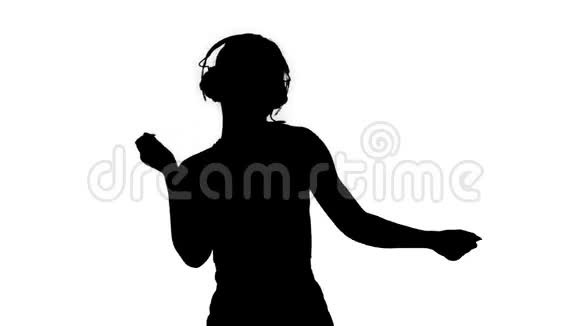 剪影年轻快乐的运动女人听音乐耳机和跳舞视频的预览图