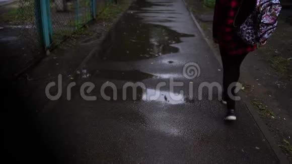 女人走进一个水池女孩在水坑里的人行道上视频的预览图