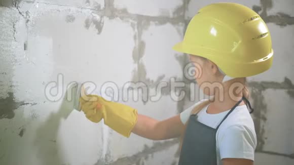 7岁的女孩戴着建筑头盔在建筑工地粉刷墙壁视频的预览图