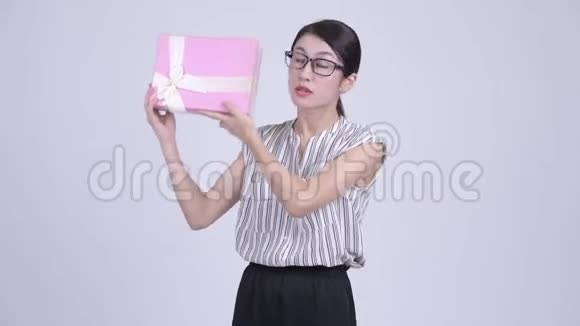 快乐美丽的亚洲女商人摇动礼品盒视频的预览图
