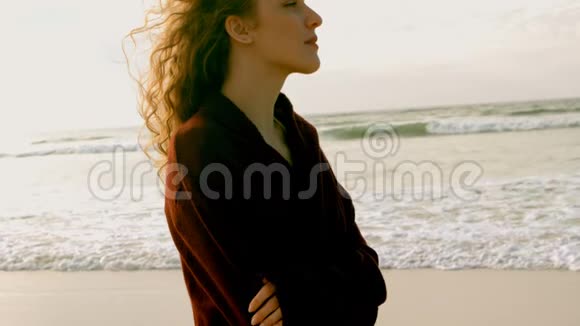 体贴的年轻白种人女人双臂交叉站在阳光下的海滩上视频的预览图